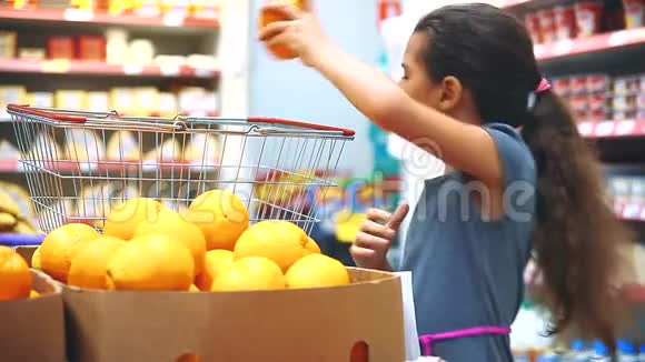在杂货店买数字平板电脑的小女孩在网上买橘子水果在超市生活的小女孩视频的预览图