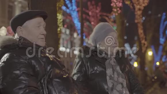 欢乐的孙子男孩跑过来在温馨的节日气氛中在圣诞夜公园拥抱老奶奶视频的预览图
