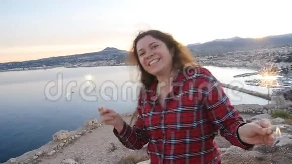 年轻快乐微笑的女人拿着火花在海边视频的预览图