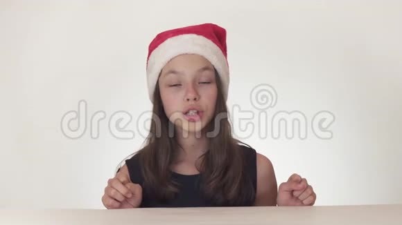 戴着圣诞老人帽子的漂亮快乐少女在白色背景股票上表达了快乐的惊喜视频的预览图
