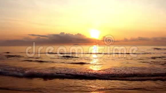 夕阳在黄昏的时候天空的黄色和橙色在海面上慢慢地在热带海滩上波浪视频的预览图