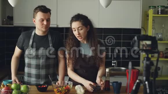 快乐有吸引力的一对夫妇在家里用数码相机录制关于健康烹饪的视频食物视频的预览图