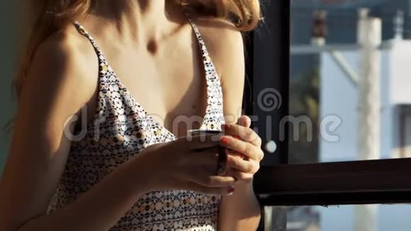 穿衬衫的女人在风中喝着美味的早晨咖啡视频的预览图