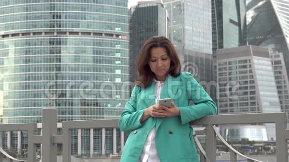 30岁的女人站在摩天大楼附近使用应用程序视频的预览图