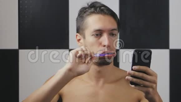 忙碌的商人在浴室刷牙使用智能手机视频的预览图