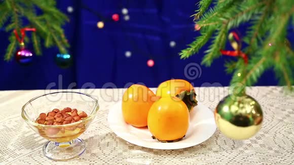 新年背景上的桌子上摆着柿子和蜜饯还有装饰过的圣诞树和牧民视频的预览图