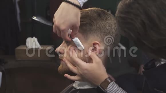 一个英俊的男人被理发师用剃刀视频的预览图