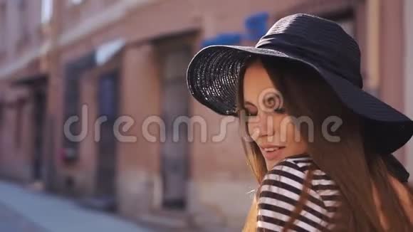 在傍晚的街道上一头长发戴着黑帽子的深黑发秀女郎视频的预览图