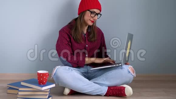 漂亮的女孩用笔记本电脑和拇指坐在家里的地板上视频的预览图