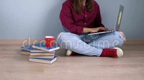 漂亮的女孩用笔记本电脑和拇指坐在家里的地板上视频的预览图