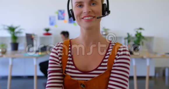 戴着耳机坐在办公桌前的漂亮白人女性高管视频的预览图