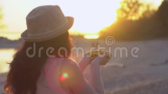 美丽的女人在海滩上缓慢地吹着纸屑快乐的少女把手中的金色闪光视频的预览图