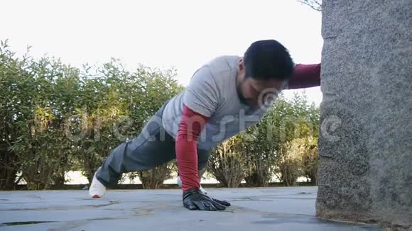 与户外私人教练一起健身健身男子在公园里做手臂俯卧撑作为锻炼常规的一部分视频的预览图