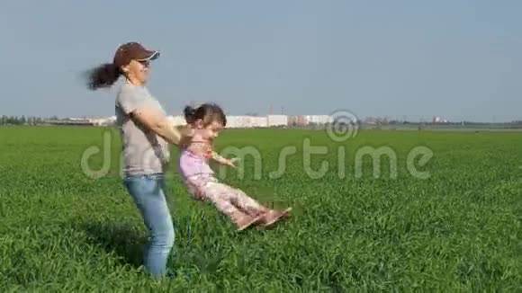 一个女人正在变成一个孩子妈妈和女儿在露天玩一个女孩带着一个孩子在草地上视频的预览图
