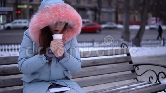 一个年轻的女人试图在寒冷的冬天用热饮料取暖视频的预览图