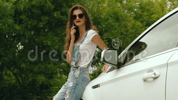 戴眼镜的时髦女士站在车旁打电话说视频的预览图