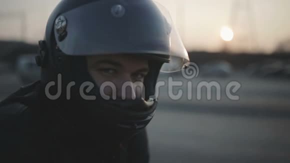 街头戴着黑色头盔的年轻漂亮摩托车手的肖像骑摩托车的人视频的预览图