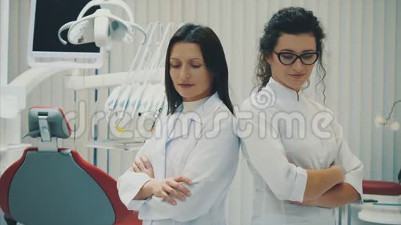 办公室里有两个牙医年轻漂亮的女人彼此站着看看相机视频的预览图