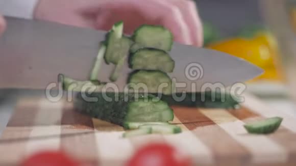 女人在砧板上切绿色黄瓜桌子上有蔬菜视频的预览图