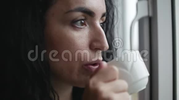 尖酸刻薄的年轻白种人女人看着窗外的雨喝着咖啡视频的预览图