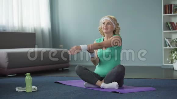 健康的成熟女性在瑜伽垫上做健身运动在家训练视频的预览图