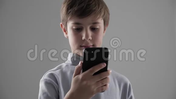 青少年1112岁男孩在白色背景下使用智能手机的肖像视频的预览图