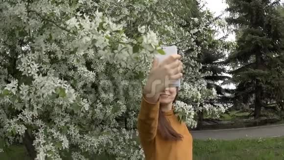 一位年轻女子慢镜头在一棵盛开的苹果树旁边自画像视频的预览图