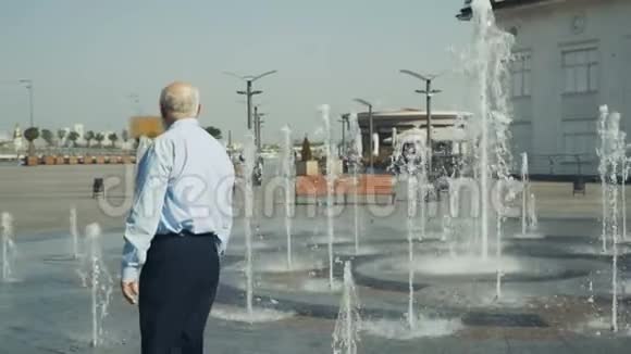 老人走在喷泉下视频的预览图