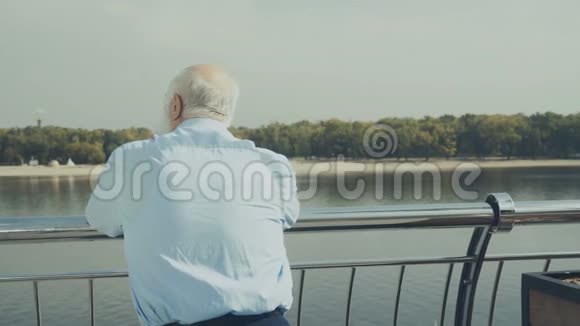 白发老人望着河边的海滩视频的预览图
