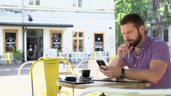男人在咖啡馆里做笔记从智能手机到笔记本滑球righ视频的预览图