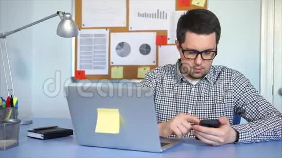 在办公室工作的人带着笔记本电脑他用智能手机查找信息视频的预览图