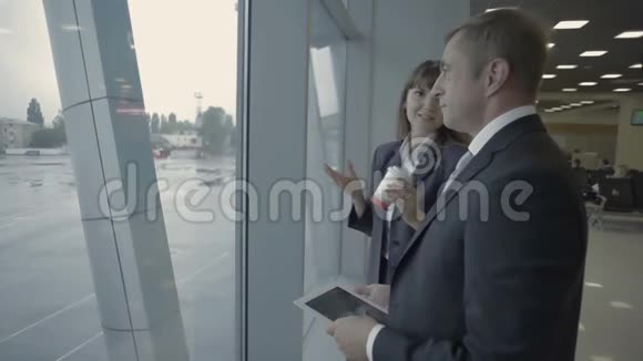 在机场窗口附近与机场员工进行平板电脑会谈的商人视频的预览图
