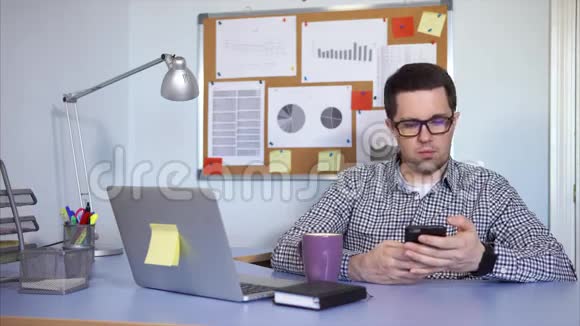 办公室工作人员坐着使用智能手机他休息一下喝咖啡视频的预览图