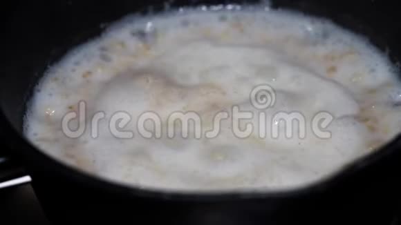 木桌上黑锅上加牛奶的燕麦片视频的预览图