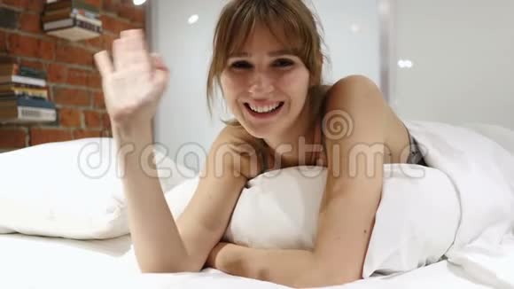 会说话的年轻女人躺在床上在线视频聊天网络摄像头查看视频的预览图