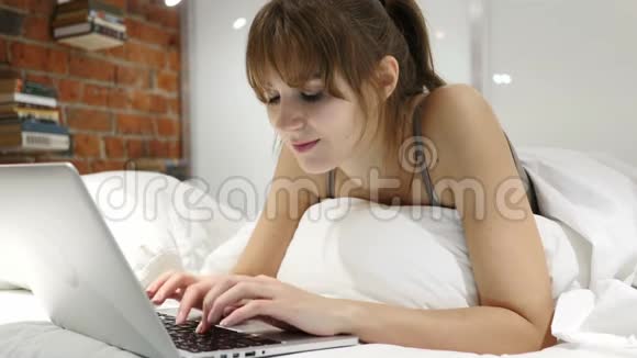 快乐的女人在床上工作在笔记本电脑和回应成功视频的预览图