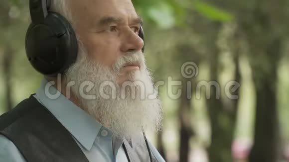 白发苍苍的老人用耳机听音乐视频的预览图