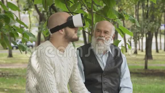 孙子和爷爷在公园里用虚拟现实眼镜视频的预览图