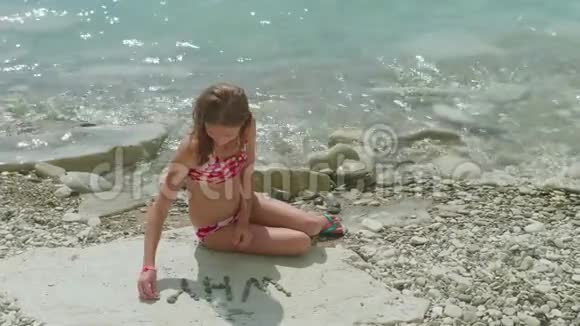 年轻的金发女孩穿着泳衣独自坐在石滩上提出了一个问题为什么视频的预览图