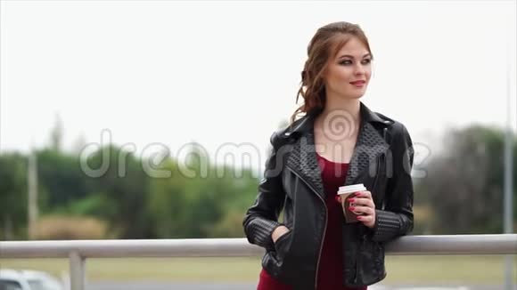 一个穿着皮夹克手里拿着咖啡的浪漫女人把目光移开视频的预览图