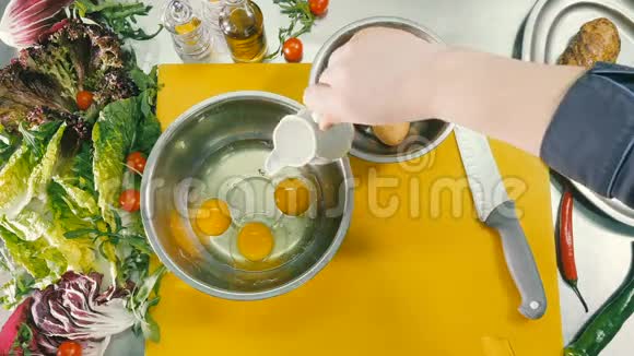 厨师在生鸡蛋里加入牛奶和胡椒粉视频的预览图