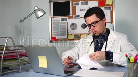 一位年轻的医生在一天结束时在私人诊所里签文件视频的预览图