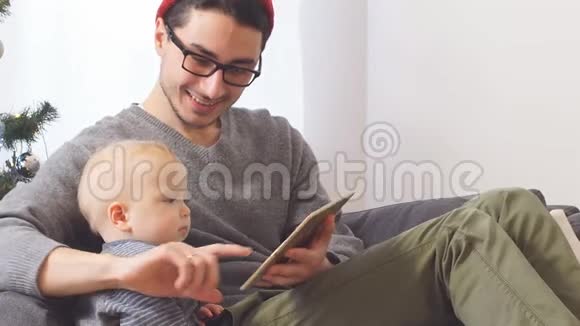 年轻的父亲和小儿子一起玩平板电脑圣诞节视频的预览图