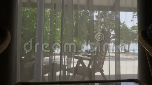 窗户有窗帘俯瞰美丽的海滩有棕榈树和海洋视频的预览图