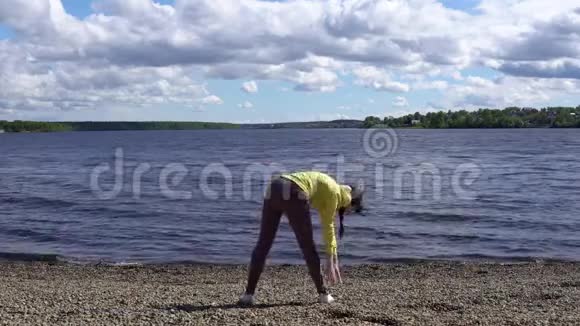 一位年轻妇女白天在湖岸从事健身活动视频的预览图