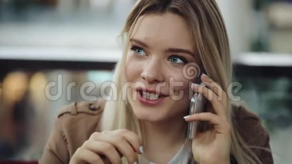 漂亮的金发女人坐在餐馆里喝奶昔打电话视频的预览图