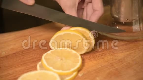 在家厨房的一个女孩的手在一个木切割板上特写在婴儿车上切一个黄柠檬家庭视频的预览图