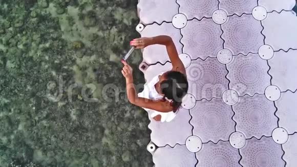 一位皮肤黝黑的年轻女游客正在用智能手机相机拍照视频的预览图