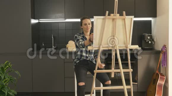 才华横溢的女艺术家在家现代厨房的画布上作画女人在家里用丙烯酸涂料画画视频的预览图