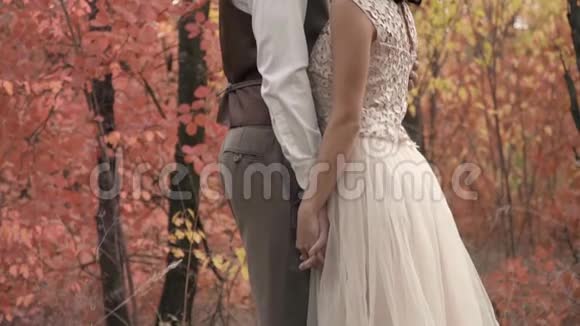 一个穿西装的男人和一个穿白衣的女人站在秋树间视频的预览图